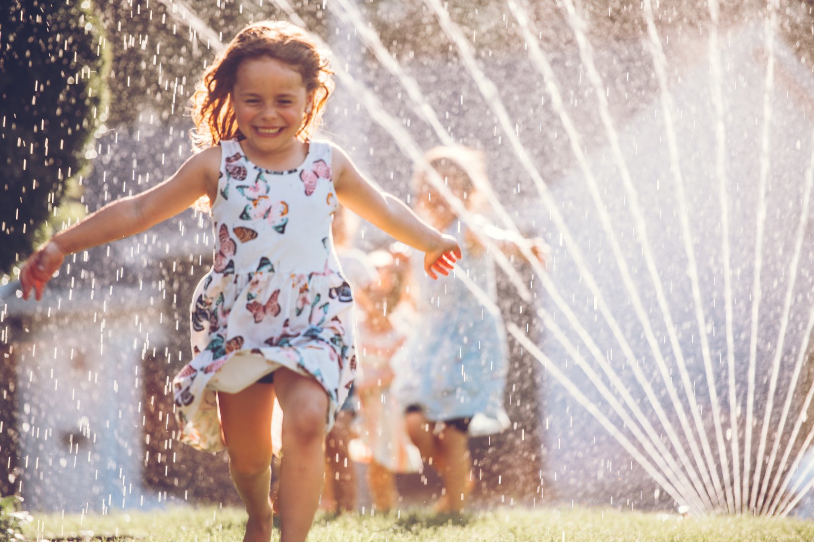 Happy kids playing with garden sprinkler